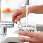 Close Up Of Woman Pouring Glass Of Water From Tap In Kitchen